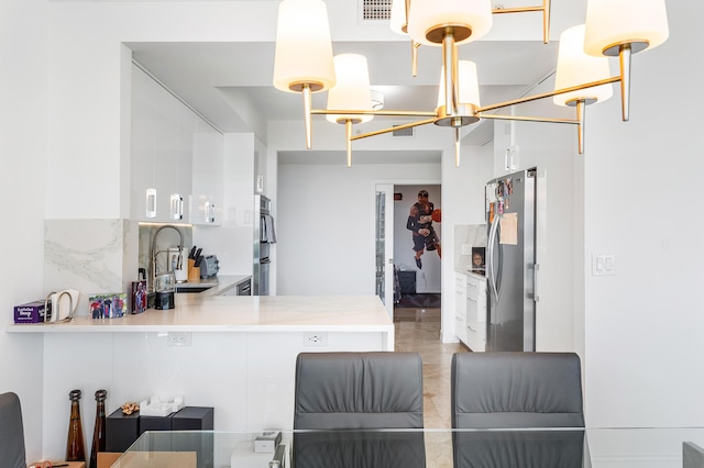 kitchen featuring visible vents, freestanding refrigerator, light countertops, white cabinetry, and a sink