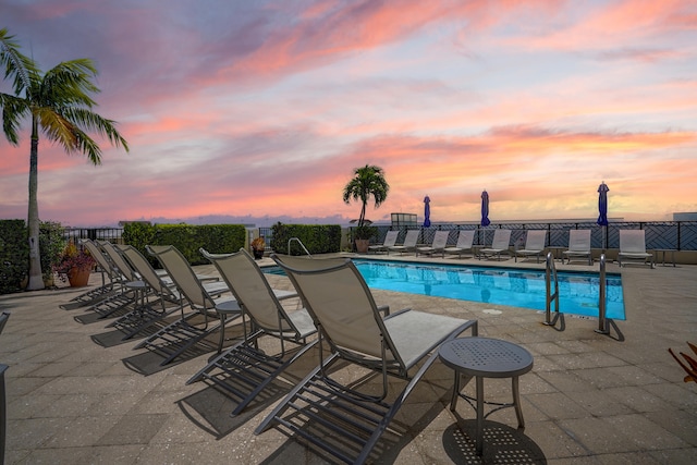 pool at dusk with a patio area