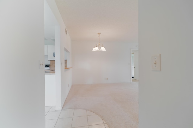 carpeted spare room featuring a notable chandelier