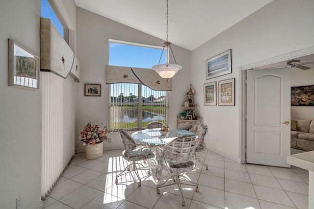 dining area featuring ceiling fan, light tile patterned flooring, a water view, and lofted ceiling