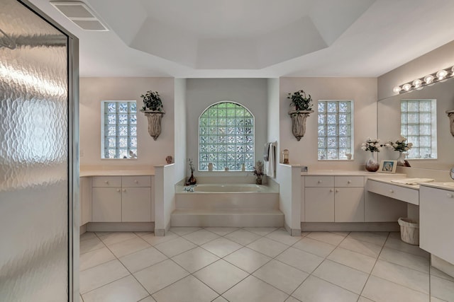 bathroom with a tray ceiling, tile patterned flooring, vanity, and a bath