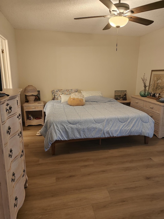 bedroom featuring ceiling fan, a textured ceiling, and wood finished floors