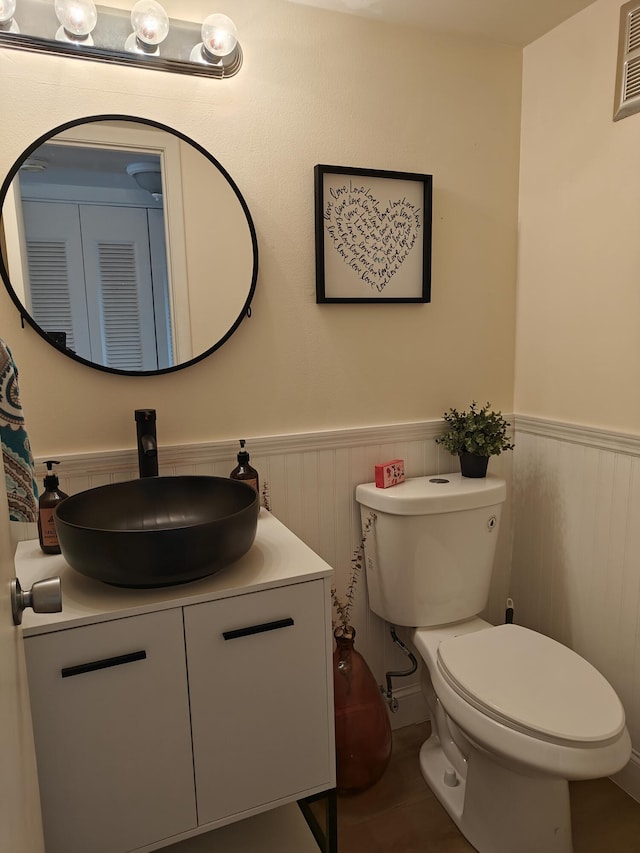 bathroom featuring vanity, toilet, and wainscoting