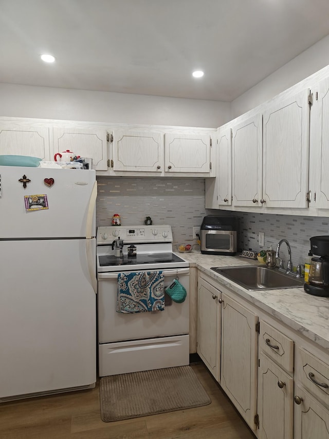 kitchen featuring tasteful backsplash, white appliances, a sink, and wood finished floors