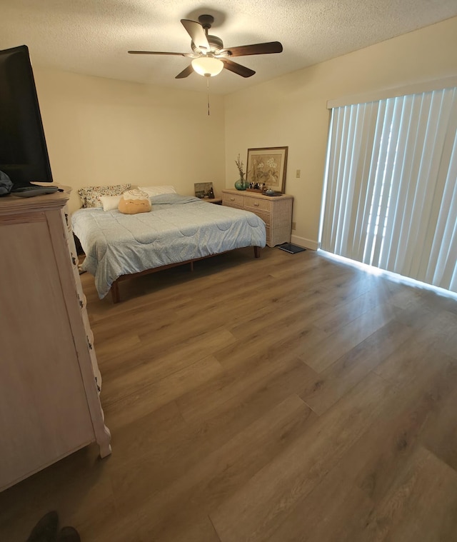 bedroom with a ceiling fan, a textured ceiling, and wood finished floors