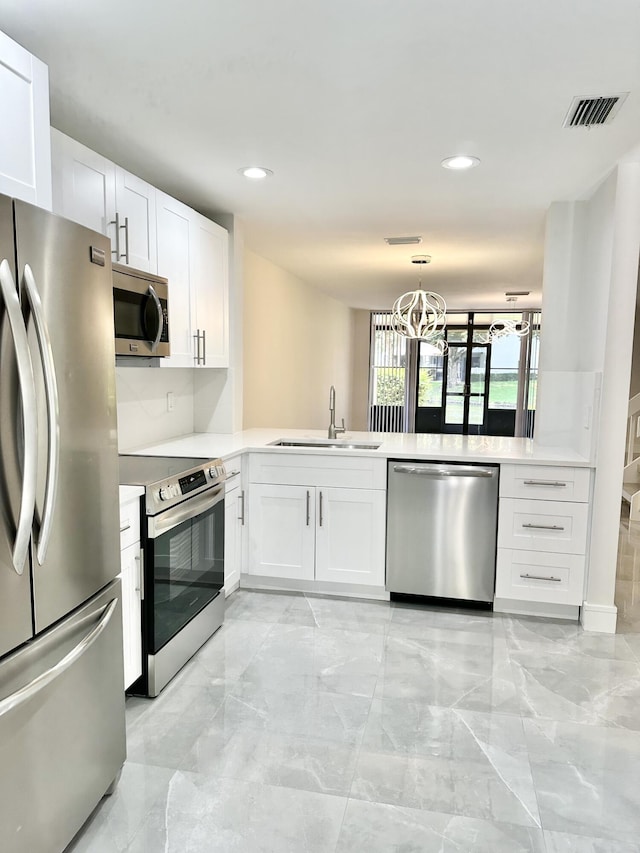 kitchen with stainless steel appliances, sink, white cabinets, and kitchen peninsula