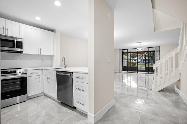 4820 NW 22nd St Unit 4134, Coconut Creek, FL 33063 - kitchen featuring appliances with stainless steel finishes, baseboards, light marble finish flooring, light countertops, and white cabinetry