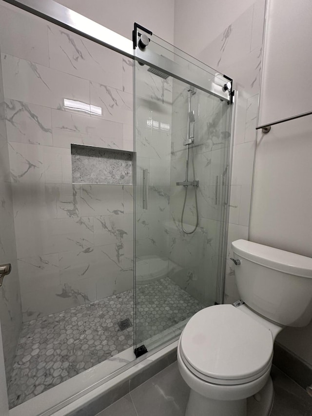 bathroom with toilet and a shower with door