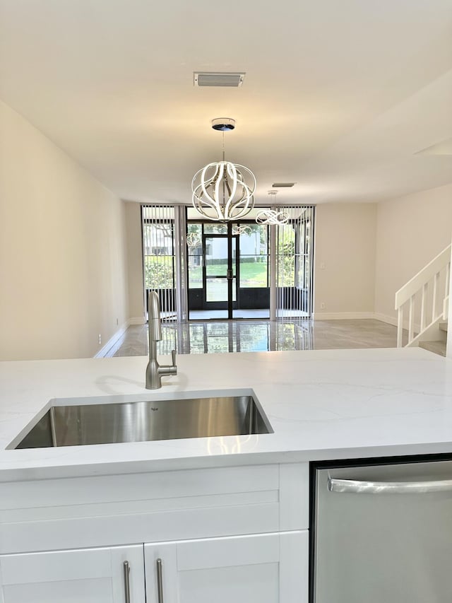 kitchen featuring light stone counters, white cabinetry, dishwasher, and sink