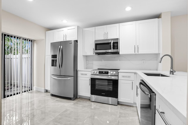 kitchen featuring a sink, appliances with stainless steel finishes, white cabinets, and light countertops