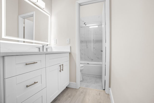 4820 NW 22nd St Unit 4134, Coconut Creek, FL 33063 - full bath with vanity, toilet, baseboards, wood finished floors, and shower / bath combination with glass door