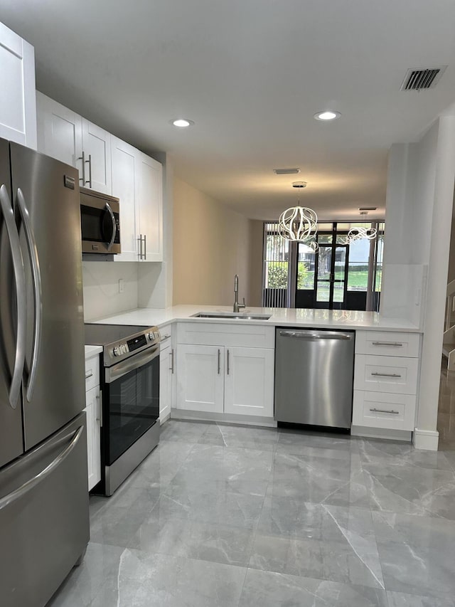 kitchen featuring sink, kitchen peninsula, white cabinets, and appliances with stainless steel finishes