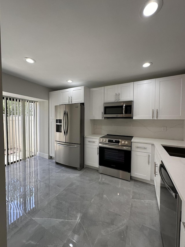 kitchen featuring white cabinetry, sink, tasteful backsplash, and stainless steel appliances