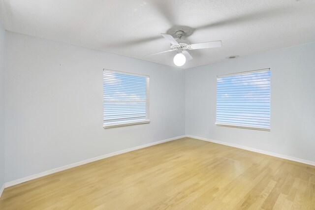 empty room featuring ceiling fan, light hardwood / wood-style flooring, and a healthy amount of sunlight