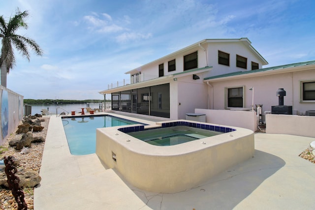 view of pool featuring a patio area, a water view, and an in ground hot tub