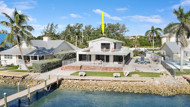 rear view of property with a sunroom, a water view, a patio area, and a lawn