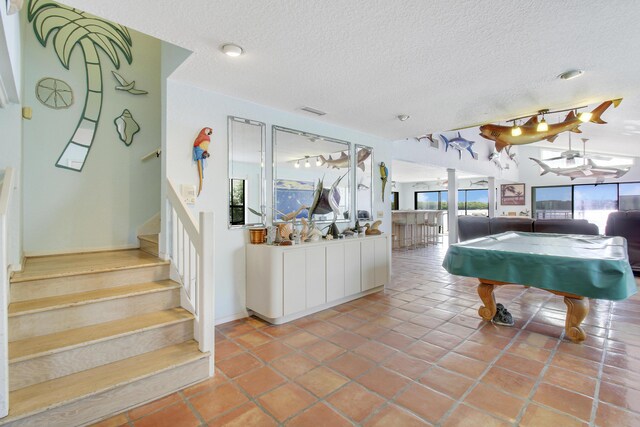 playroom with a textured ceiling, pool table, and tile patterned floors