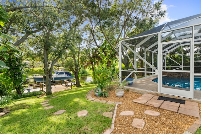 view of yard with glass enclosure, a patio area, and a boat dock