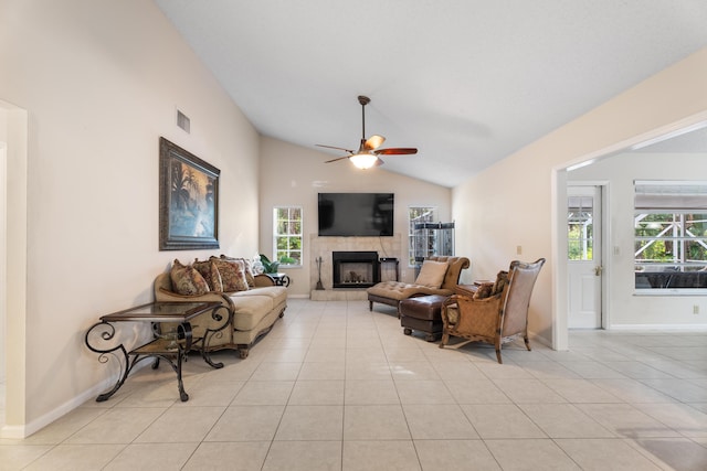 living room with a healthy amount of sunlight, vaulted ceiling, a tile fireplace, and light tile patterned floors