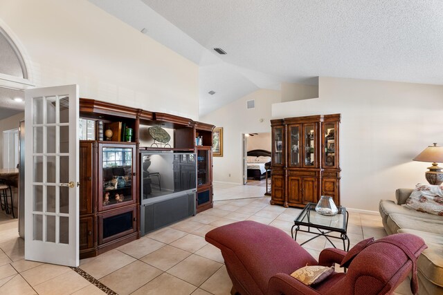 tiled entrance foyer featuring vaulted ceiling, french doors, and a textured ceiling