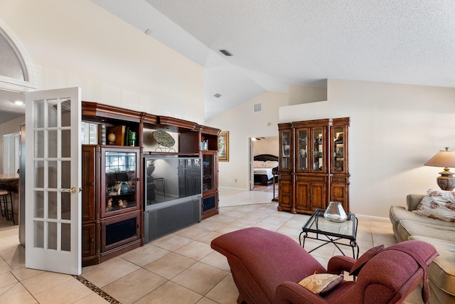 living room featuring light tile patterned floors, high vaulted ceiling, and a textured ceiling