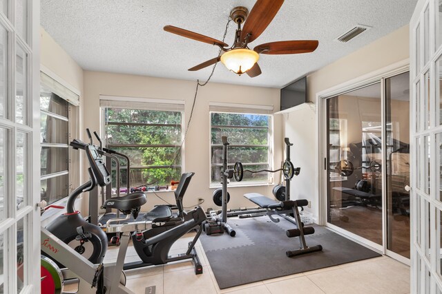 tiled bedroom with a textured ceiling, a fireplace, ceiling fan, and multiple windows