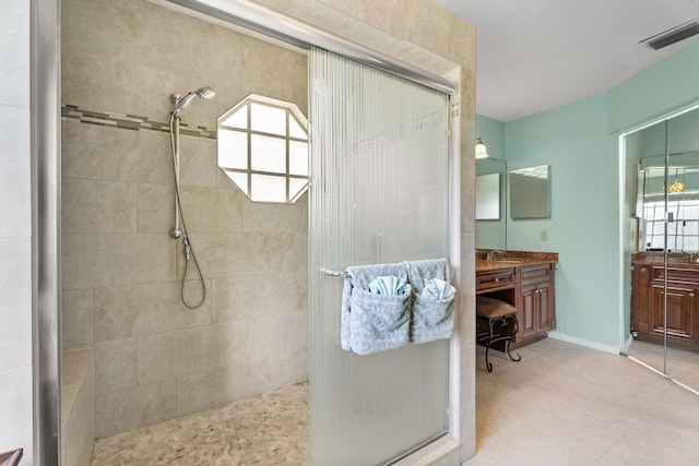 bathroom with tiled shower, vanity, and tile patterned flooring