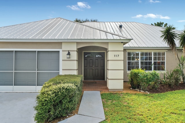 entrance to property with a garage and a lawn