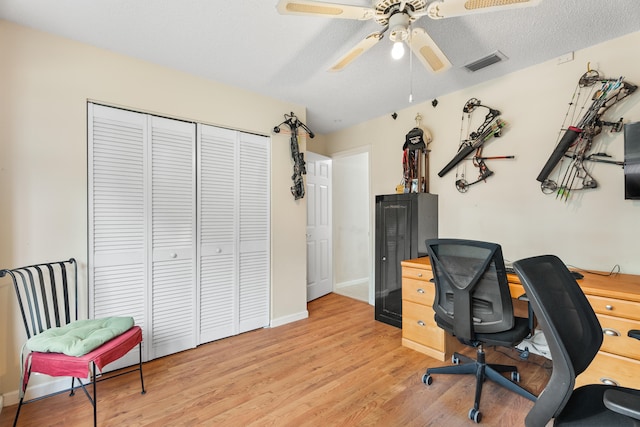 office with a textured ceiling, light wood-type flooring, and ceiling fan