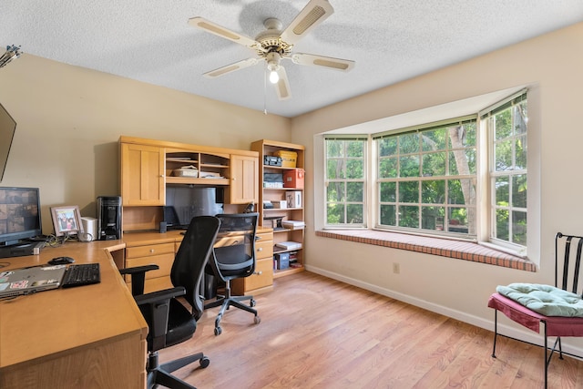 home office featuring ceiling fan, a healthy amount of sunlight, a textured ceiling, and light wood-type flooring