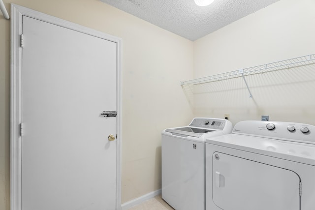 laundry room with washing machine and dryer, a textured ceiling, and light tile patterned floors