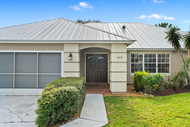 entrance to property featuring a yard and a garage