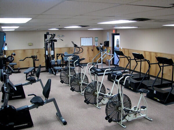 exercise room with a drop ceiling and wood walls