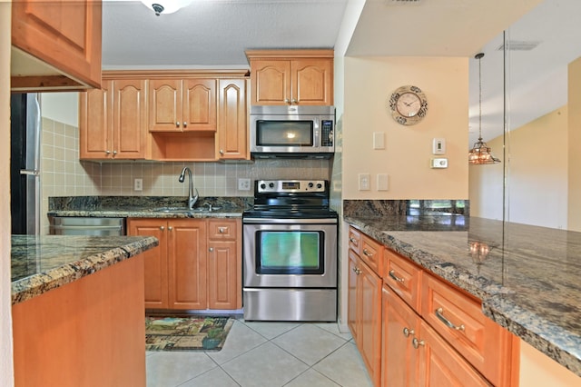 kitchen with stainless steel appliances, tasteful backsplash, dark stone countertops, and decorative light fixtures