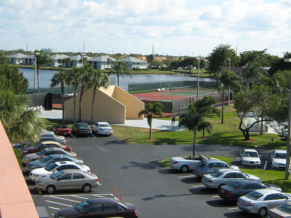 view of vehicle parking featuring tennis court and a water view