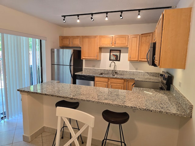 kitchen featuring rail lighting, stainless steel appliances, sink, and light stone countertops