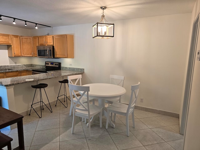 dining room with a notable chandelier, light tile patterned flooring, track lighting, and a textured ceiling