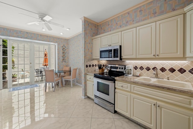 kitchen featuring ceiling fan, cream cabinetry, sink, decorative backsplash, and appliances with stainless steel finishes