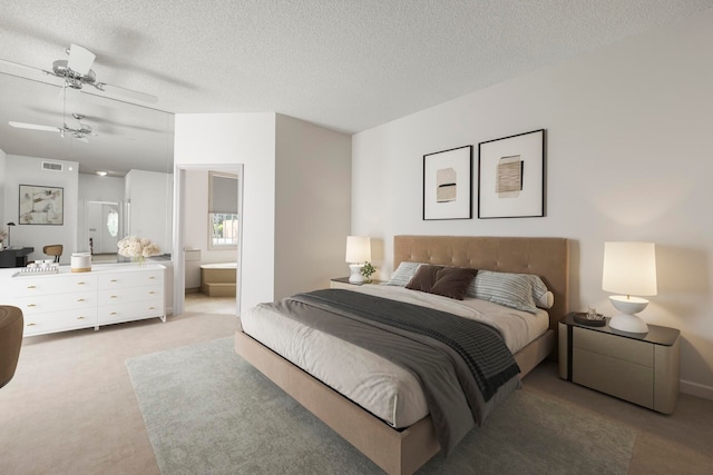 bedroom with ceiling fan, light colored carpet, a textured ceiling, and ensuite bath