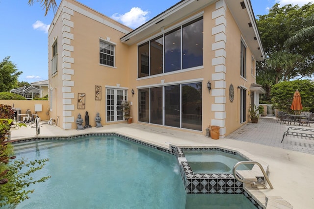 back of property with a patio area, a pool with connected hot tub, and stucco siding