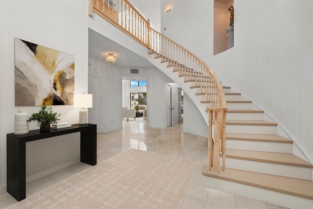 stairs featuring tile patterned flooring and a towering ceiling