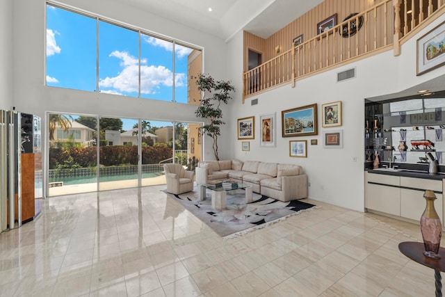 living room featuring sink, a towering ceiling, and light tile patterned floors