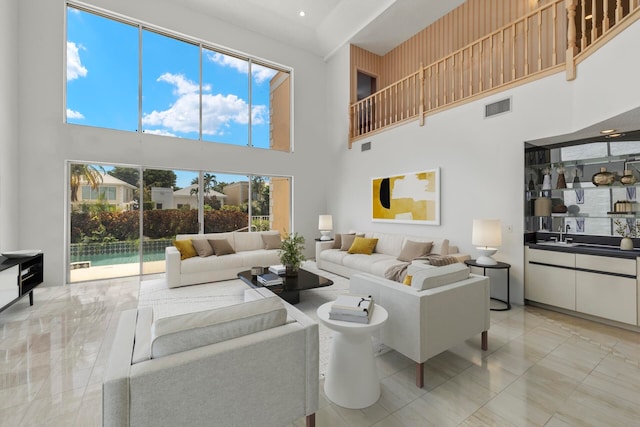 living room featuring sink, plenty of natural light, a towering ceiling, and light tile patterned floors