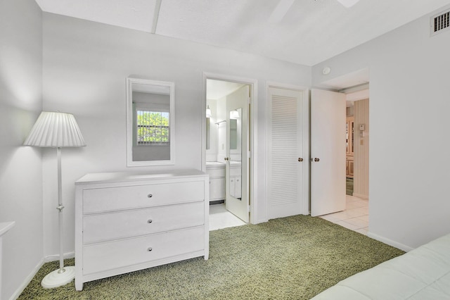 tiled bedroom featuring ensuite bath and ceiling fan