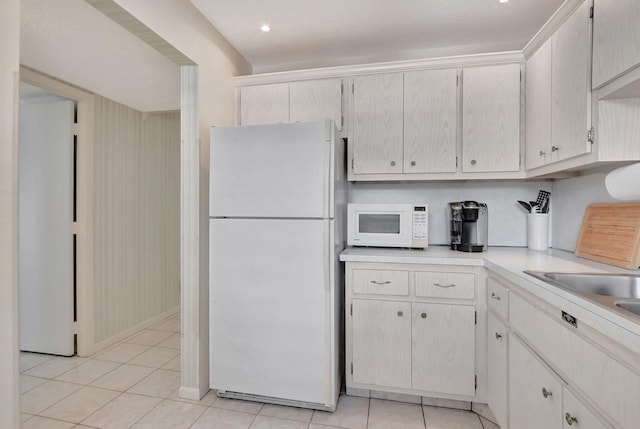 kitchen featuring light tile patterned flooring, white cabinets, and white appliances