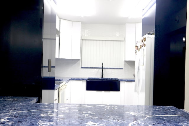 kitchen with tasteful backsplash, white cabinetry, sink, white fridge with ice dispenser, and stove