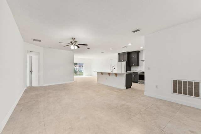 unfurnished living room with sink, light tile patterned floors, and ceiling fan