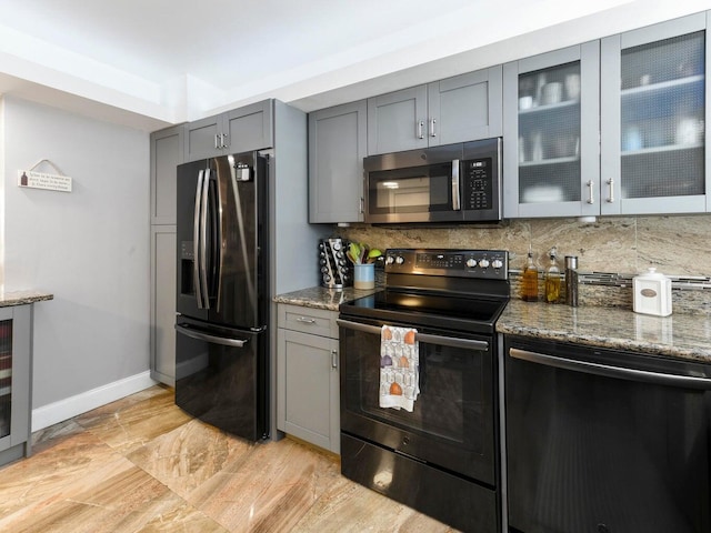 kitchen featuring stone counters, black appliances, decorative backsplash, and gray cabinetry