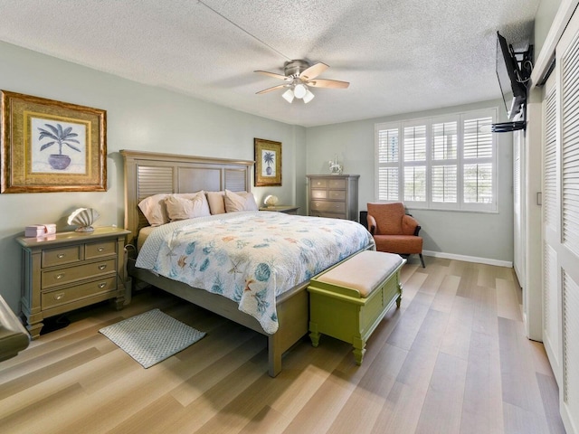 bedroom featuring light wood-type flooring, ceiling fan, a closet, and a textured ceiling