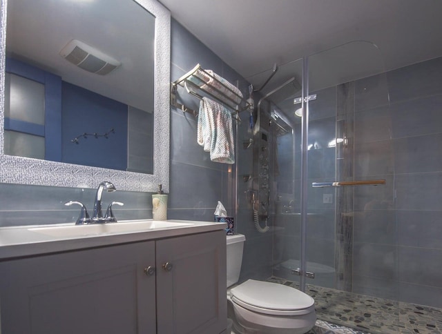 bathroom featuring a shower with shower door, vanity, and toilet